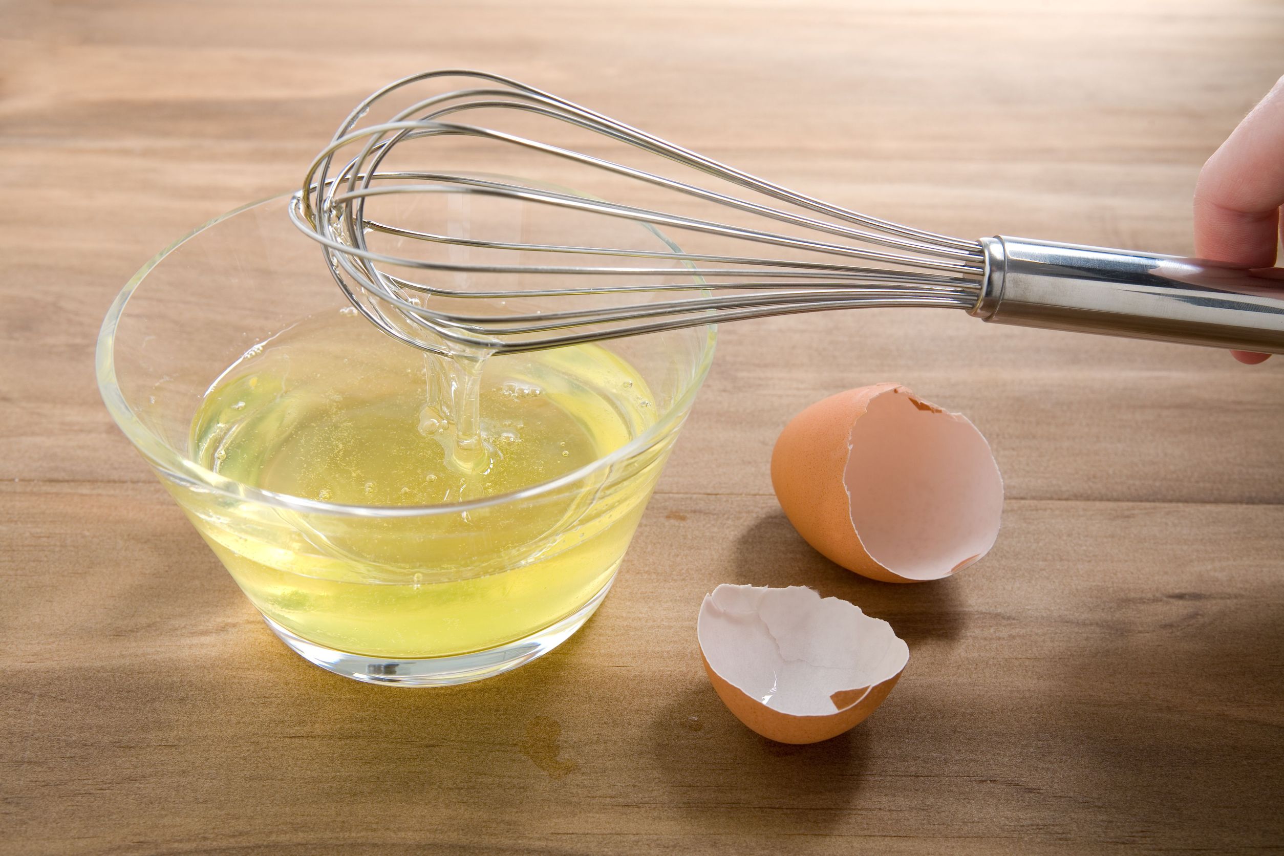 1172957 – raw egg whites just cracked into a glass bowl waiting to be whisked